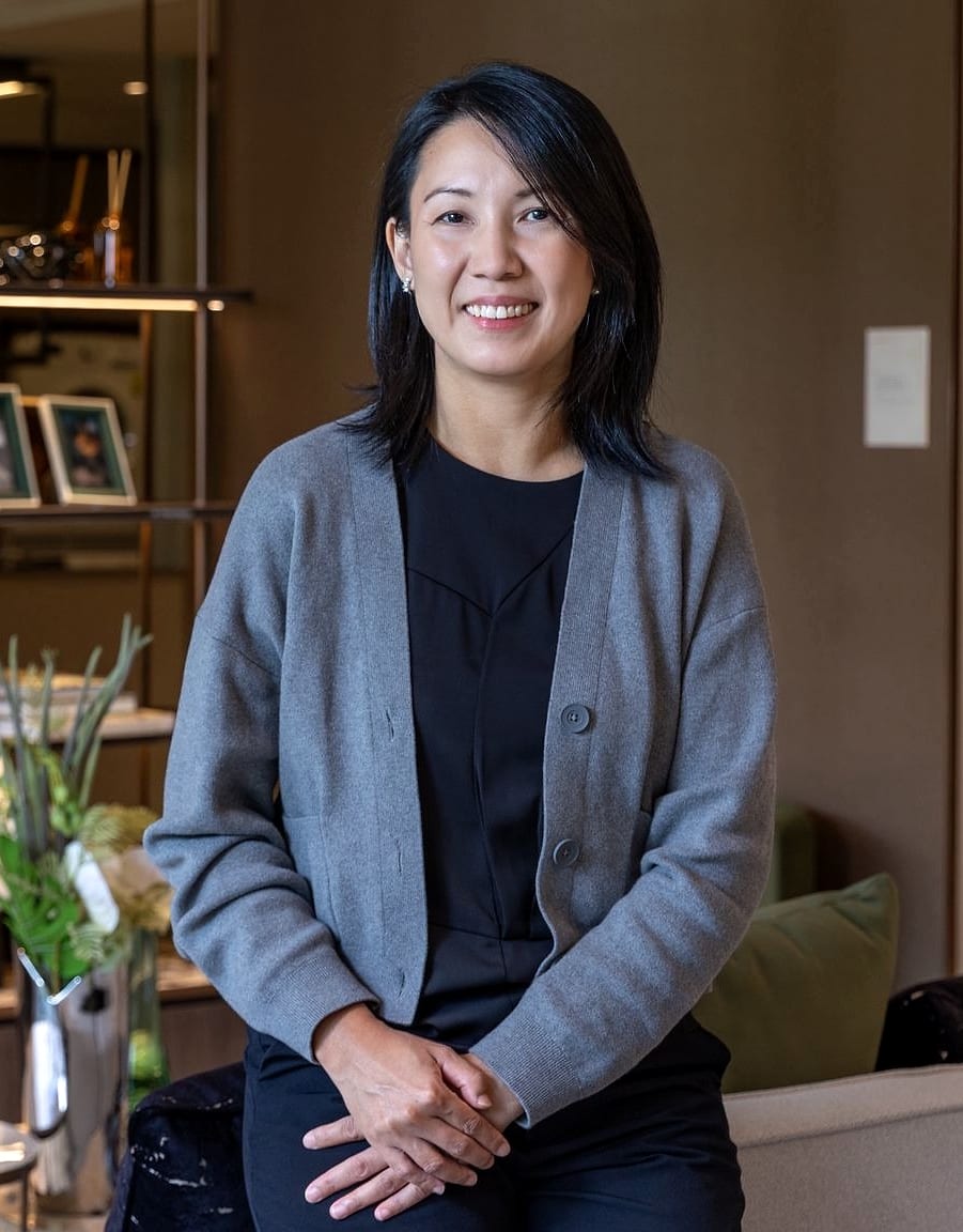 Renee Sim, seated in a Singapore showflat, wearing a grey cardigan over a black top.